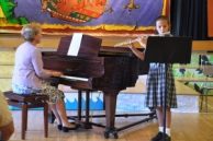 girl playing flute next to a woman playing piano