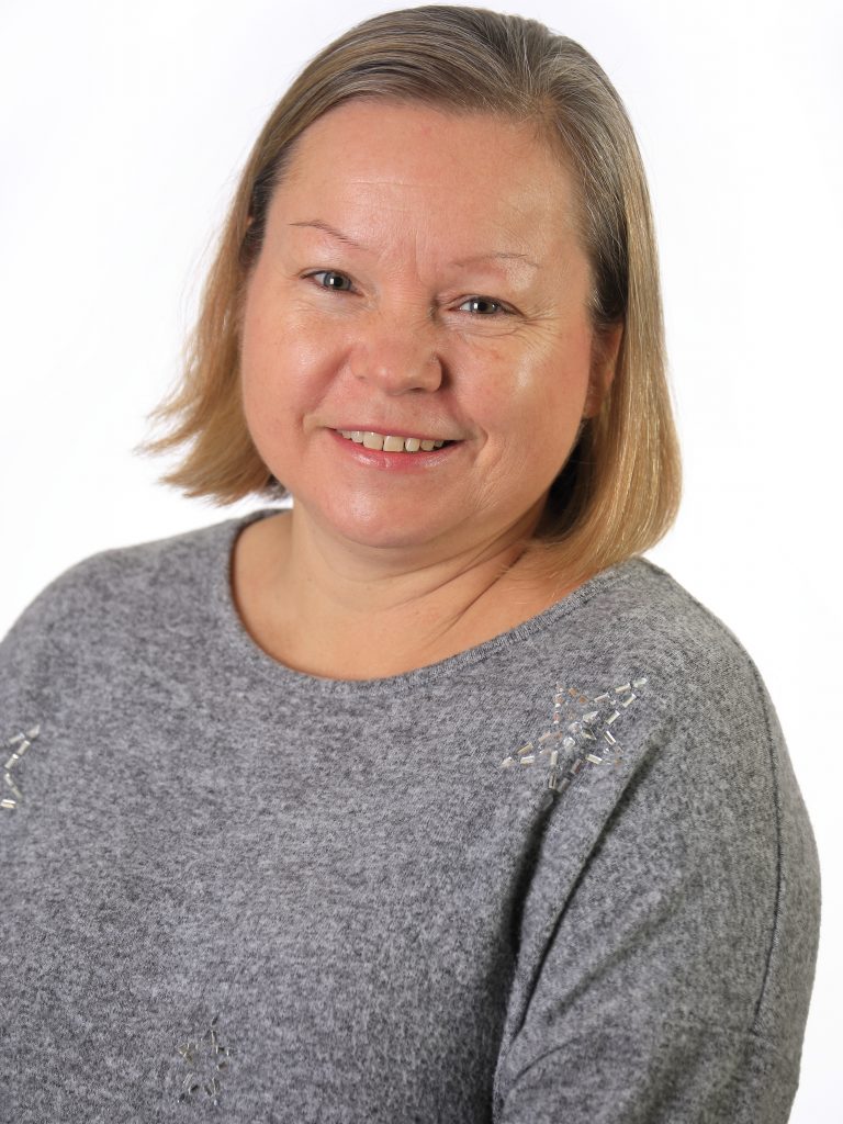 Photo of a smiling woman with short blonde hair and a grey jumper