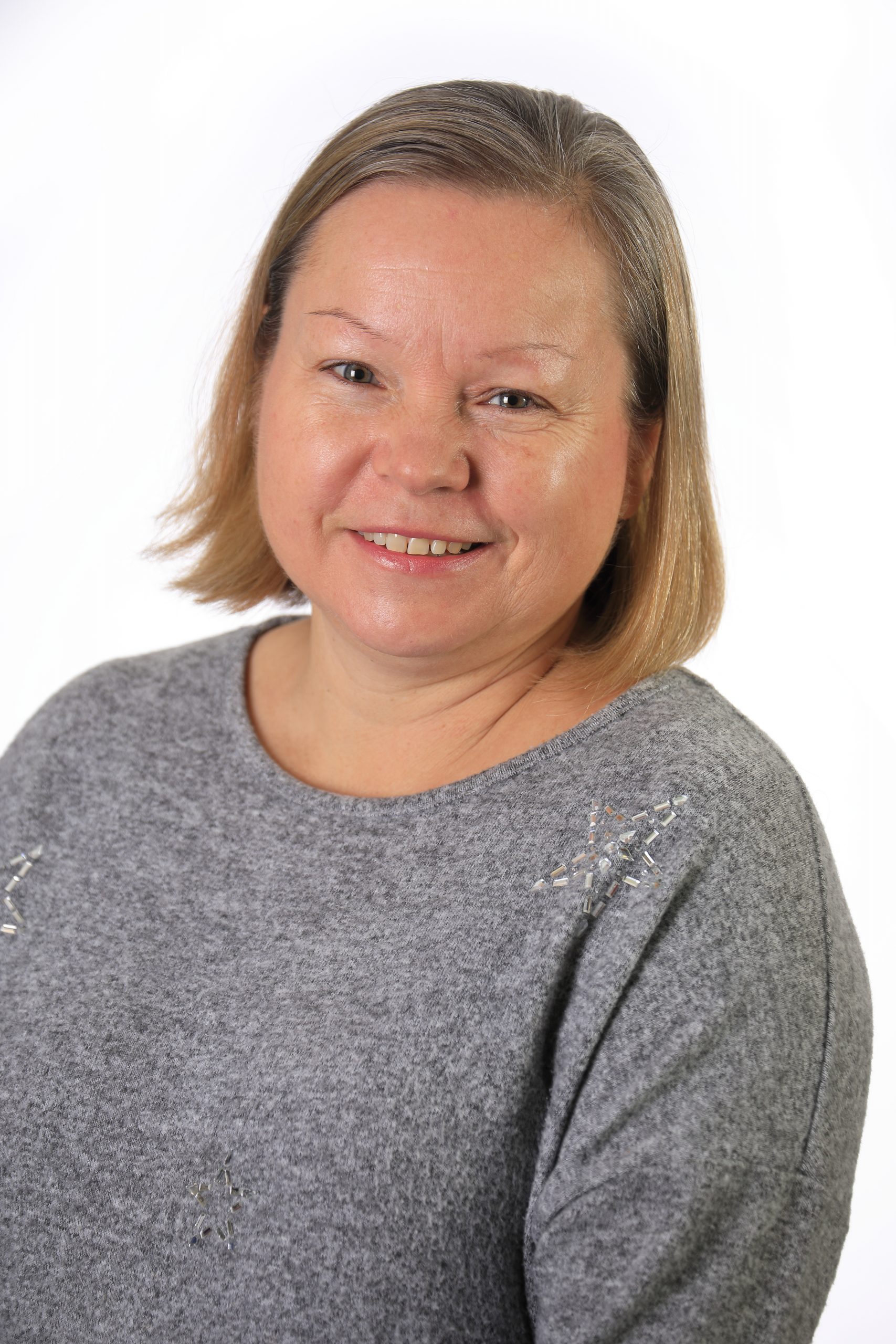 Photo of a smiling woman with short blonde hair and a grey jumper