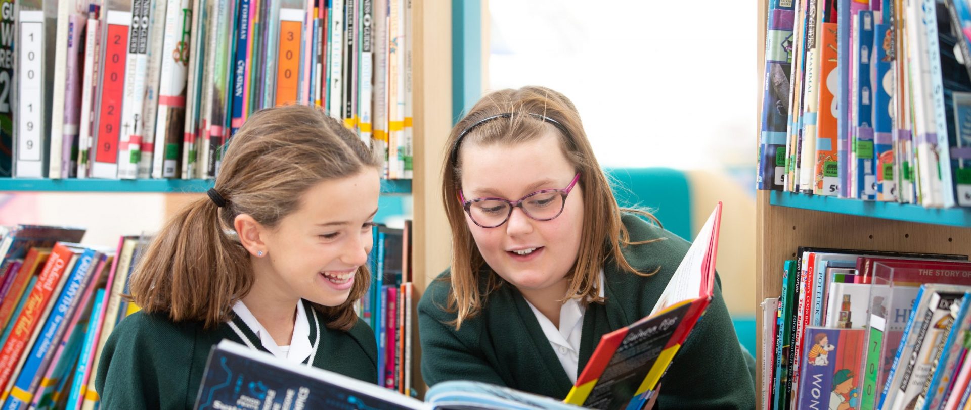 two girls reading books in the school library