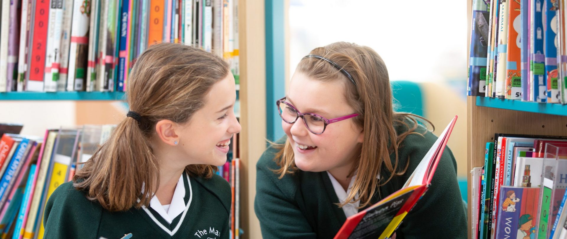 two girls reading in the library at school