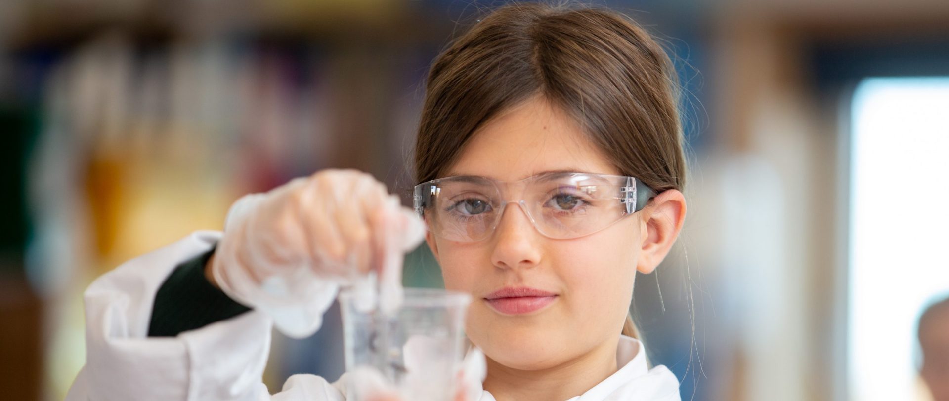 A student in a science class, measuring solutions into a container