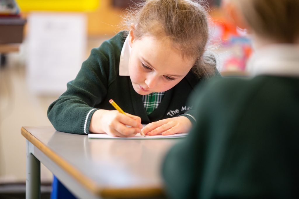 school girl writing with a pencil during lessons