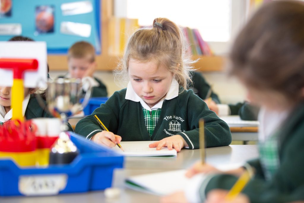 young child writing in a classroom