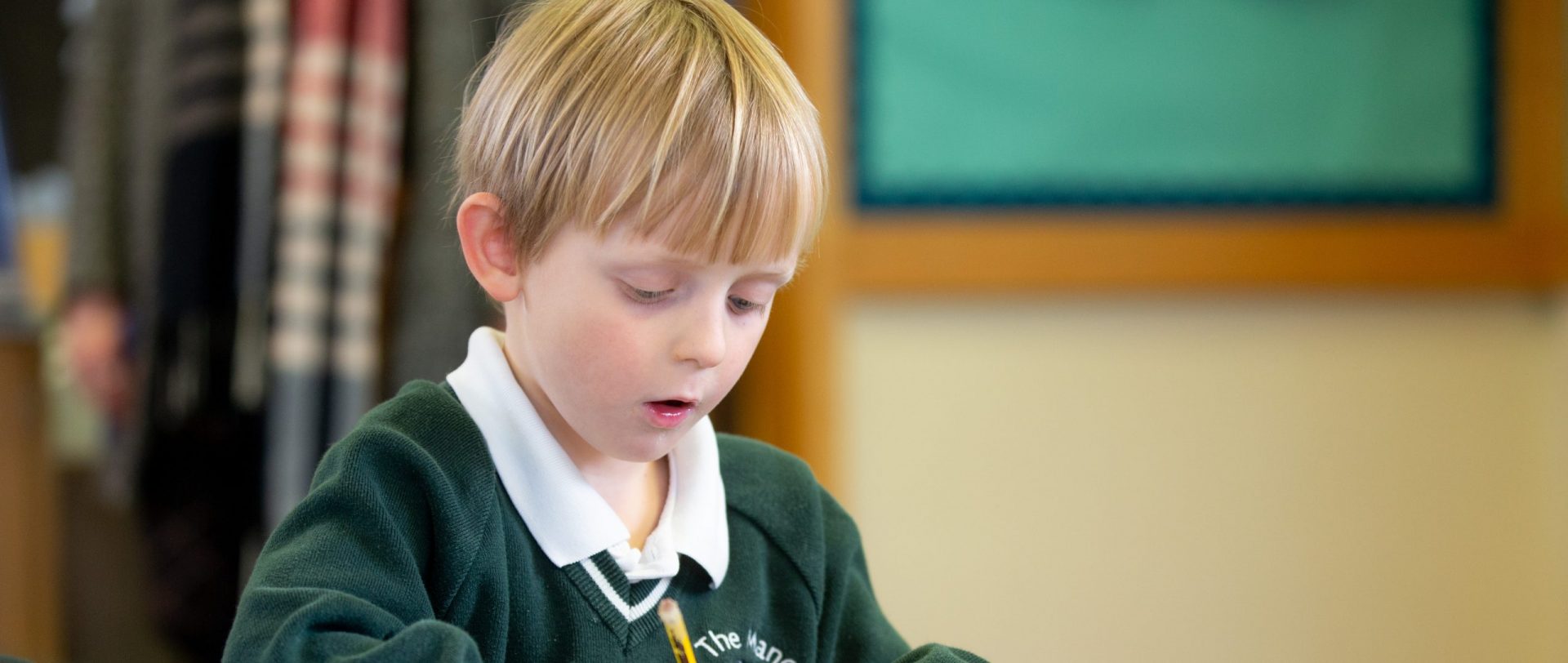 young child writing with a pencil at school