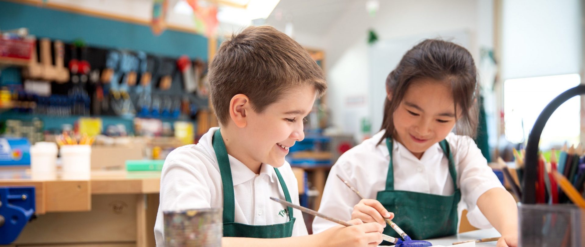 2 students painting a pebble with dark blue paint