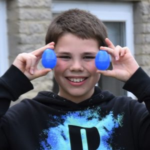 Student holding 2 blue balls in his hands