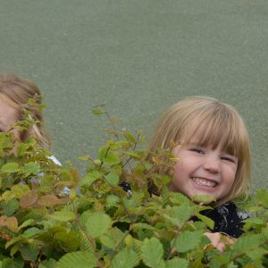 girls hiding behind a bush